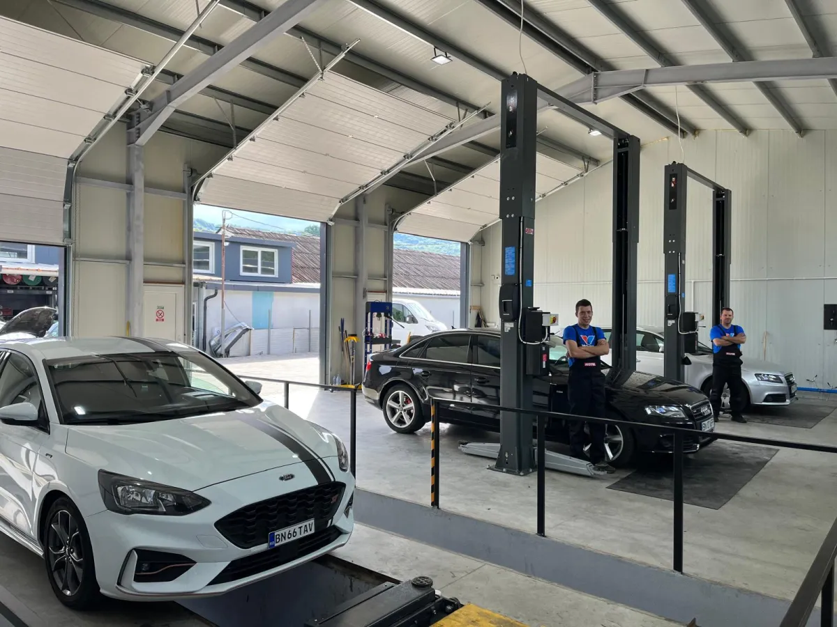 Service auto modern, cu mai multe elevatoare și mașini pregătite pentru intervenții tehnice.
